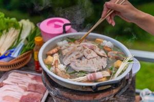 een persoon kookt voedsel in een pan met eetstokjes bij ภูชมดาว ม่อนแจ่ม in Mon Jam
