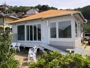 mały biały dom z białymi krzesłami przed nim w obiekcie Villa SHIRATO / Vacation STAY 35977 w mieście Iwaya