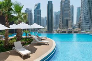 een zwembad met stoelen en parasols en een skyline van de stad bij Primestay - Jumeirah Living Marina Gate 1BR Prime Location with Waterfront Views Direct access to Marina Walk in Dubai