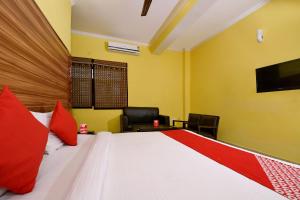 a bedroom with a bed with red pillows and a tv at OYO Flagship Maira Residency in Dehradun