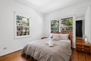 a white bedroom with a large bed with two windows at Sea Corner in Anglesea