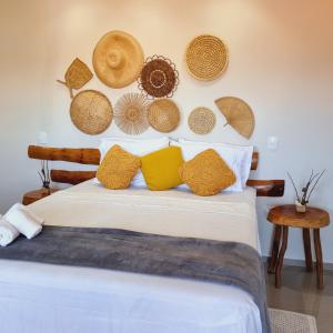 a bed with yellow pillows and hats on the wall at Pousada La Vita in São Miguel dos Milagres