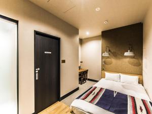 a bedroom with a bed and a black door at H HOTEL in Fukuoka