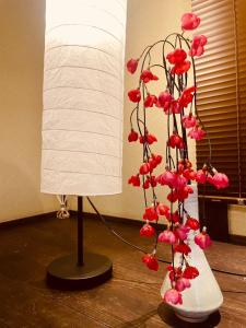a lamp with a plant with red flowers in a vase at SAMURISE KURA in Fujikawaguchiko