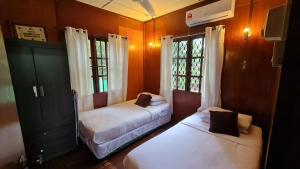 twee bedden in een kamer met twee ramen bij Kampong Style Homestay Pengkalan Balak - Sea View in Pengkalan Balak