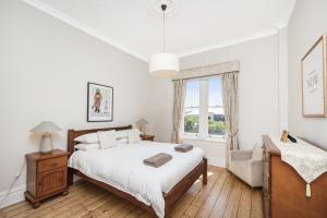 - une chambre blanche avec un grand lit et une fenêtre dans l'établissement Apartment Faro, à Fremantle