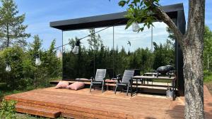 eine Holzterrasse mit Stühlen und einem Tisch mit Grill in der Unterkunft Juniper Minivillas - Standard and Lux in Söderby