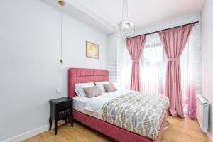 ein Schlafzimmer mit einem rosa Bett und einem Fenster in der Unterkunft HCG Art'Muse Apartment in Batumi