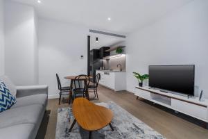 a living room with a couch and a tv and a table at The Eminence Apartments by CLLIX in Melbourne