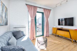 ein Wohnzimmer mit einem Sofa und einem TV in der Unterkunft HCG Art'Muse Apartment in Batumi