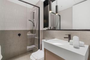 a bathroom with a sink and a toilet and a mirror at The Eminence Apartments by CLLIX in Melbourne