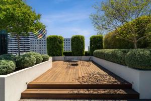 a wooden walkway with a table in a garden at The Eminence Apartments by CLLIX in Melbourne