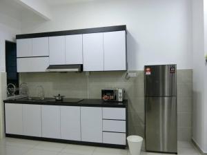 a kitchen with white cabinets and a stainless steel refrigerator at Atlantis Residence @ Icon Stay Melaka in Malacca