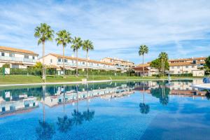 a large swimming pool with palm trees and buildings at Lujoso Chalet Golf Panoramica in San Jorge