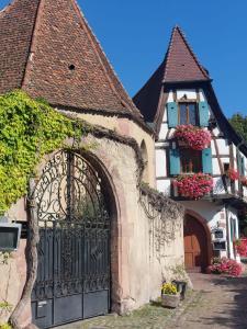 een gebouw met een poort en een huis met bloemen bij la Parenthèse Kaysersberg in Kaysersberg