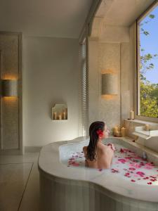 a woman sitting in a bath tub in a bathroom at ITC Gardenia, a Luxury Collection Hotel, Bengaluru in Bangalore