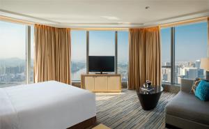 恵州市にあるRenaissance Huizhou Hotelのベッドとテレビが備わるホテルルームです。