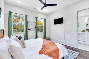 a white bedroom with a bed and a tv at Modern Mid-city Maison in New Orleans