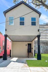 una casa blanca con una puerta negra en Modern Mid-city Maison en Nueva Orleans