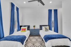 two beds in a room with blue curtains at Le Chateau Miro in New Orleans