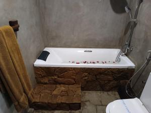 a bathroom with a bath tub with a stone wall at Negombo Boutique Villa in Negombo