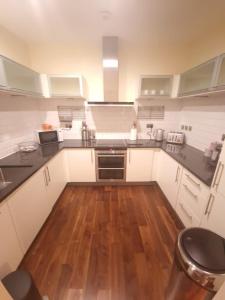 cocina con armarios blancos y suelo de madera en Ravishing Riverside 2-Bed Rental in Canary Wharf en Londres