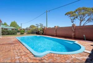 ein Swimmingpool in einem Garten neben einem Zaun in der Unterkunft Somerville Secure Accommodation in Kalgoorlie