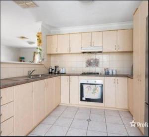 a kitchen with white cabinets and a stove at Somerville Secure Accommodation in Kalgoorlie