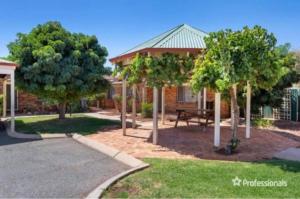 a house with trees and a picnic table in front of it at Somerville Secure Accommodation in Kalgoorlie