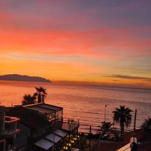 una puesta de sol sobre el agua con palmeras y un edificio en Lulubay Rooms & Suites, en Kusadasi