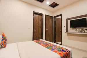 a bedroom with a bed and a flat screen tv at FabHotel Rosewood Inn in Amritsar