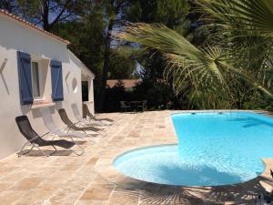 a swimming pool on a patio with chairs and a building at Le Mazet De Trial in Aubais