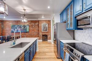 uma cozinha com armários azuis e uma parede de tijolos em Carnival Condo em Nova Orleans