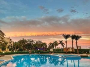 ein großer Pool mit Palmen und Sonnenuntergang in der Unterkunft Chez Sam in Sharm El Sheikh