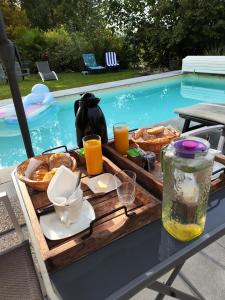 uma bandeja de comida numa mesa ao lado de uma piscina em La Soranaise, chambre chez habitant à la campagne em Sorans-lès-Breurey