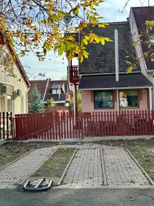 une maison avec une clôture rouge et une paire de chaussons dans l'établissement Andrea Apartman, à Bük