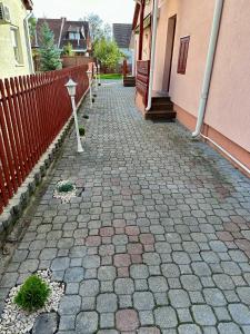 a brick sidewalk next to a building with a fence at Andrea Apartman in Bük