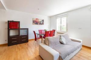 a living room with a couch and a table with red chairs at MUI Pamplona in Pamplona