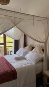 1 dormitorio con cama con dosel, sábanas y almohadas blancas en Sepeda Hostel en Canggu