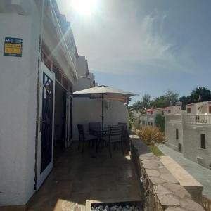 eine Terrasse mit einem Tisch und einem Sonnenschirm in der Unterkunft QUIET DUPLEX CLOSE to the BEACH in Playa de las Americas