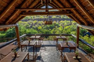 une terrasse avec des tables et des chaises et un lustre dans l'établissement Sediba Luxury Safari Lodge, à Réserve animalière Welgevonden