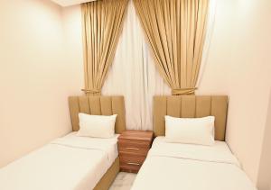 duas camas num quarto com cortinas em الدانة للشقق الفندقية em Kuwait