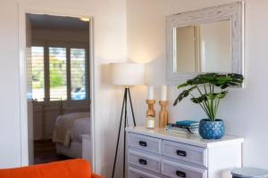 a bedroom with a dresser with a lamp and a mirror at Bermagui Townhouse - Amazing views & location in Bermagui