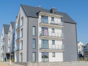 un gran edificio de apartamentos blanco con techo negro en Apartament Morski Wiatr, en Ustronie Morskie