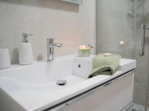 a white bathroom with a sink and a mirror at Apartament Morski Wiatr in Ustronie Morskie