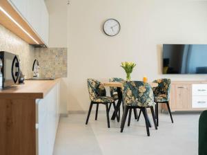 a kitchen with a table and chairs with a clock on the wall at Apartament Morski Wiatr in Ustronie Morskie