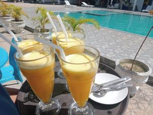 Sunny Fish Hotel في Kallady: مجموعة من المشروبات على طاولة بالقرب من حمام السباحة