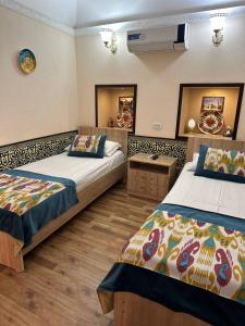 a hotel room with two beds and a mirror at Khurjin Old Karavansaray in Bukhara