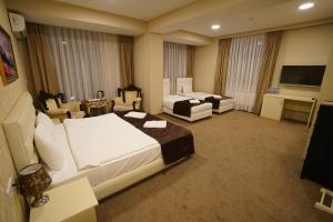 Cette chambre comprend deux lits et une télévision. dans l'établissement Shahdag Quba & Truskavets, à Quba