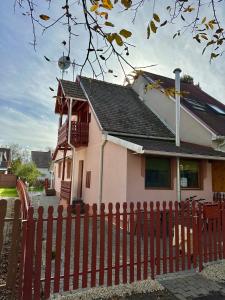 une maison avec une clôture rouge devant elle dans l'établissement Andrea Apartman, à Bük